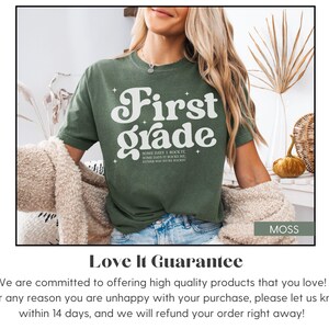 Puede incluir: Camiseta verde musgo con las palabras "First Grade" en una fuente retro. La camiseta tambi&eacute;n tiene el texto "Some days I rock it, some days it rocks me, either way we're rockin". La camiseta tiene un ajuste c&oacute;modo.