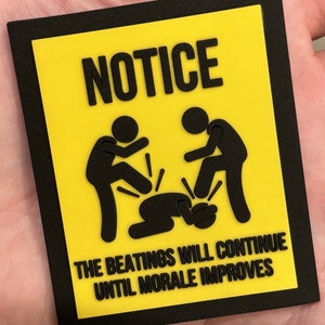 May include: A yellow and black sign with the word "NOTICE" in black lettering. The sign features a stick figure illustration of two people kicking a third person on the ground. The text below the illustration reads "THE BEATINGS WILL CONTINUE UNTIL MORALE IMPROVES."