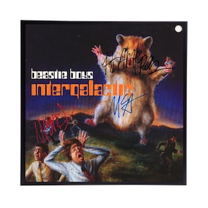 May include: A black and white album cover with a large hamster jumping in the air. The album cover is for the Beastie Boys album "Intergalactic". The album cover is signed by the Beastie Boys.