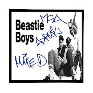 May include: Black and white photo of three men, two sitting on a skateboard and one standing in the air. The men are wearing casual clothing and the photo is signed "Beastie Boys" in black and "M.E.A.  " and "MIKE D" in blue.