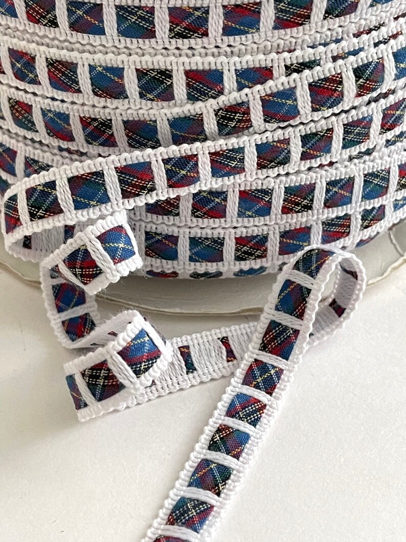 May include: White trim with a red, blue, and yellow plaid pattern. The trim is folded and shows the pattern on both sides.