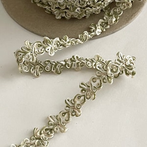 May include: A close-up of a white and green decorative trim with a floral design. The trim is made of a soft, pliable material and is perfect for adding a touch of elegance to any project.