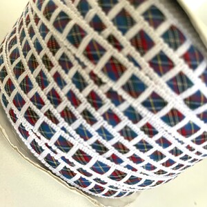 May include: A roll of white and blue plaid ribbon with a white woven design. The ribbon has a checkered pattern.