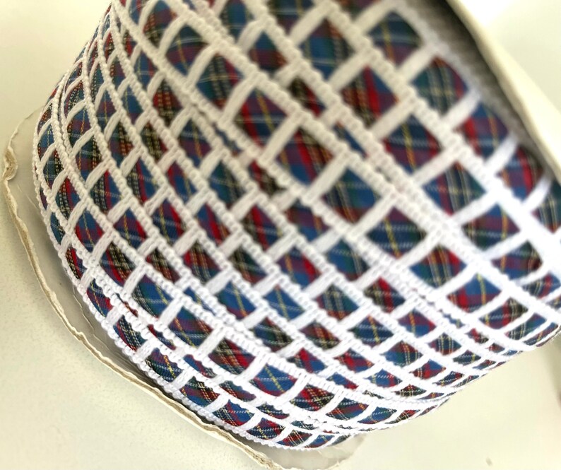 May include: A roll of white and blue plaid ribbon with a white woven design. The ribbon has a checkered pattern.
