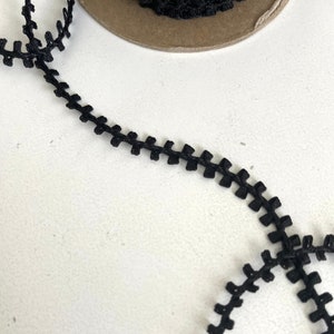 May include: Black zig-zag trim with a scalloped edge. The trim is made of a soft, flexible material and is perfect for adding a touch of detail to any project.
