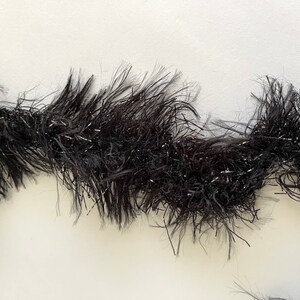 May include: Black tinsel garland with a sparkly finish. The garland is made of thin, wispy strands of tinsel that are twisted together.