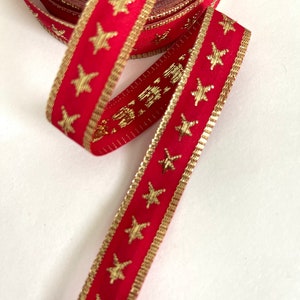Puede incluir: Cinta roja con estrellas doradas. La cinta est&aacute; enrollada y se ha desenrollado un tramo de la cinta.