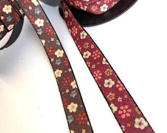 May include: Two spools of brown and burgundy floral patterned ribbon with black trim. The ribbon is approximately 1 inch wide.