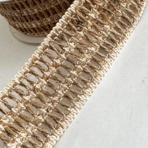 May include: A close-up of a natural fiber ribbon with a woven design. The ribbon is made of a combination of brown and white fibers, creating a textured look.