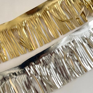 May include: Two strips of fringe trim, one gold and one silver. The fringe is made of thin, metallic strips.