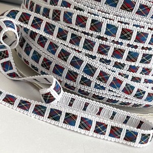 May include: White trim with a red, blue, and yellow plaid pattern. The trim is folded into a coil.