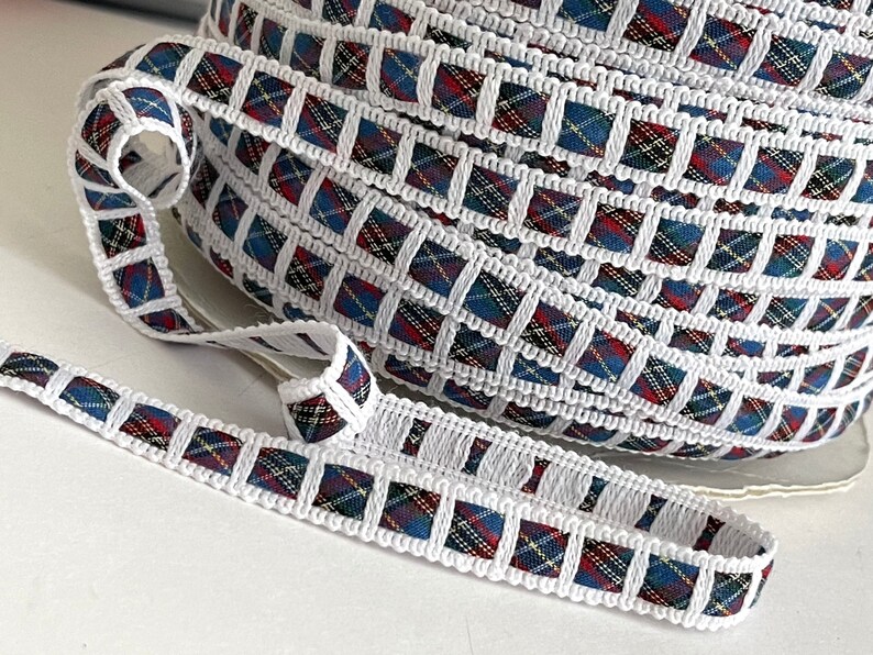 May include: White trim with a red, blue, and yellow plaid pattern. The trim is folded into a coil.