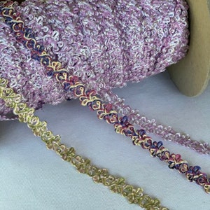 May include: Three spools of decorative trim with a floral design. The trim is in shades of purple, green, and gold.