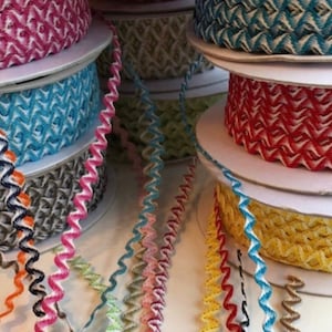 May include: Assortment of colorful, patterned, and textured trim ribbon spools. The ribbon is wavy and has a zig-zag pattern.