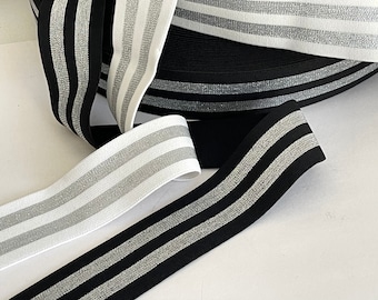 May include: Three rolls of elastic trim with silver glitter stripes. One roll is black, one is white, and one is a combination of black and white.