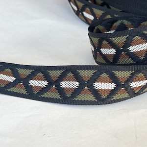 May include: Black and green patterned ribbon with a diamond design. The ribbon has white and brown accents.