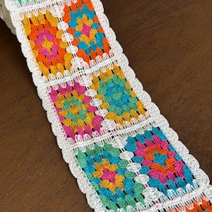 May include: White crochet trim with colorful granny squares in shades of orange, pink, teal, green, and yellow.