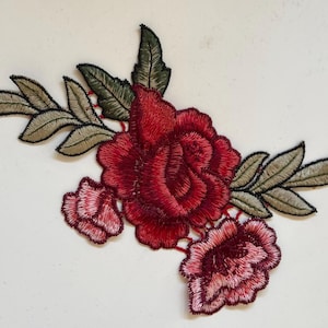 May include: Red embroidered rose flower applique with green leaves. This floral patch is perfect for adding a touch of elegance to clothing, bags, or home decor projects.