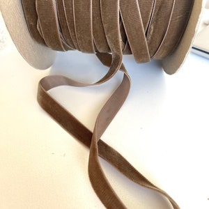May include: A spool of brown velvet ribbon. The ribbon is soft and has a subtle sheen. It is perfect for adding a touch of elegance to any project.