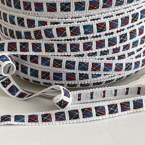 May include: White trim with a red, blue, and yellow plaid pattern. The trim is rolled up and shows the pattern repeating.