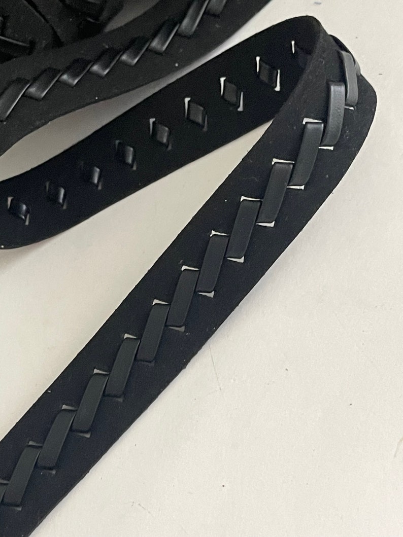 May include: Black braided leather trim with a diamond pattern cut-out. The trim is approximately 1 inch wide.