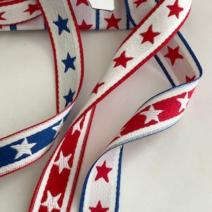 May include: Two red, white, and blue striped ribbons with white stars. The ribbon on the top has red stars and the ribbon on the bottom has blue stars.