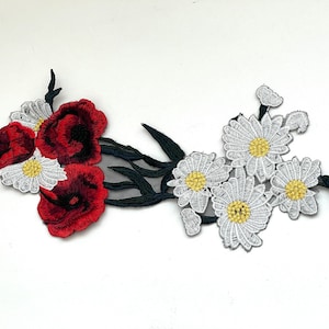 May include: Red and white embroidered flower applique with a black mesh background. The applique features three red poppies and five white daisies.