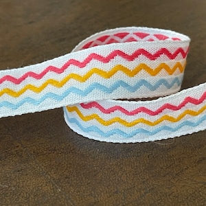 May include: White ribbon with a chevron pattern in red, yellow, and blue.