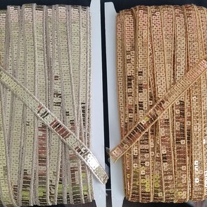 May include: Two spools of gold-colored trim with sequins. The trim on the left spool is a lighter gold color, while the trim on the right spool is a darker gold color.