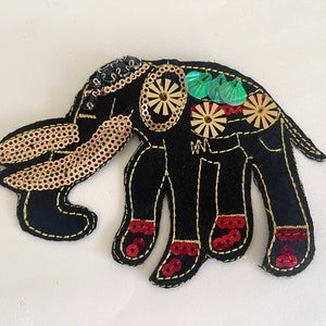 May include: Black felt elephant applique with gold and green sequins. The elephant has red sequins on its feet.