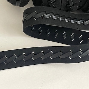 May include: Black braided leather trim with a stitched design. The trim is approximately 1 inch wide.