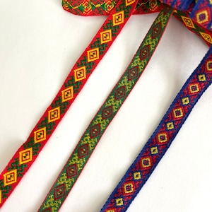 May include: Three different patterned ribbon trims with red, green, blue, yellow, and gold colors. The trims have a geometric diamond pattern.