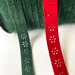 May include: Two spools of decorative trim with a floral cut-out design. One spool is green and the other is red.