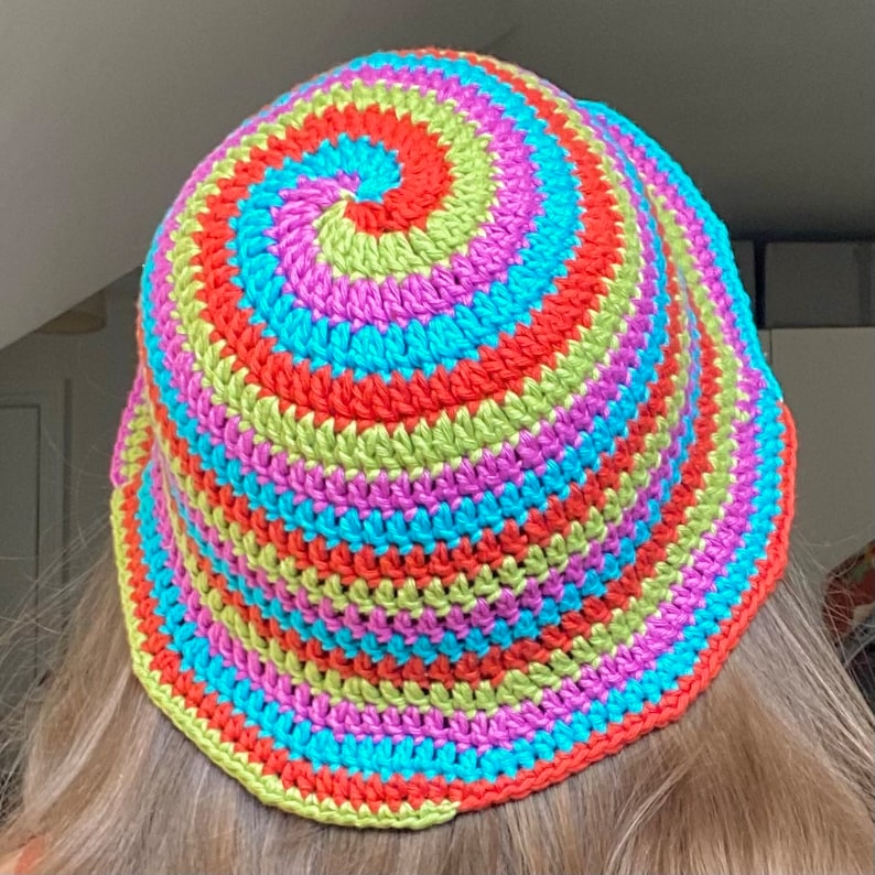 May include: A colorful crocheted bucket hat with a spiral pattern in shades of green, pink, blue, and orange.