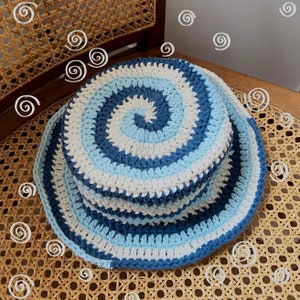 May include: A blue and white crocheted bucket hat with a spiral pattern.