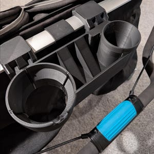 May include: A black stroller organizer with two cup holders, a compartment, and a phone holder. The organizer attaches to the stroller handle. A blue and black phone holder is attached to the stroller handle.