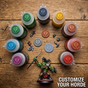 May include: A collection of ten circular paint pots with colored lids featuring a sword and wing emblem, arranged in a circle around three small circular tokens and a green-skinned miniature warrior holding a paintbrush. Text reads CUSTOMIZE YOUR HORDE.