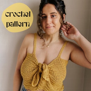 May include: A mustard yellow crochet top with a knotted front and thin straps. The top is cropped and has a wavy hemline.