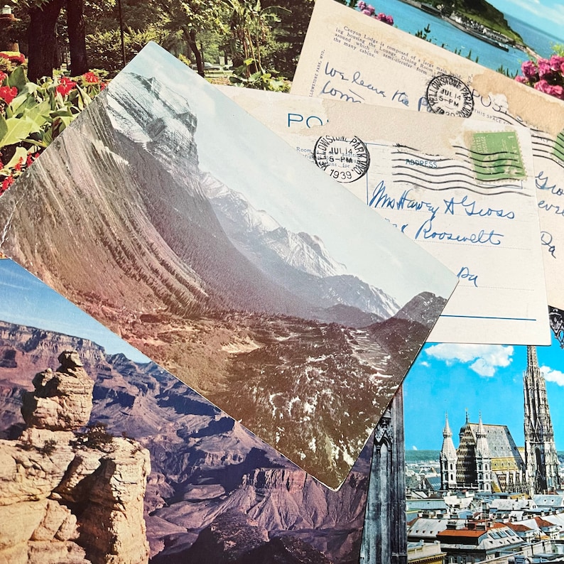 May include: A vintage postcard featuring a scenic mountain landscape with a snow-capped peak. The postcard is partially obscured by another postcard with handwritten text and a stamp dated July 14, 1939.