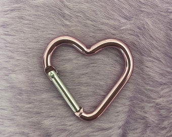 May include: A rose gold heart-shaped carabiner clip.