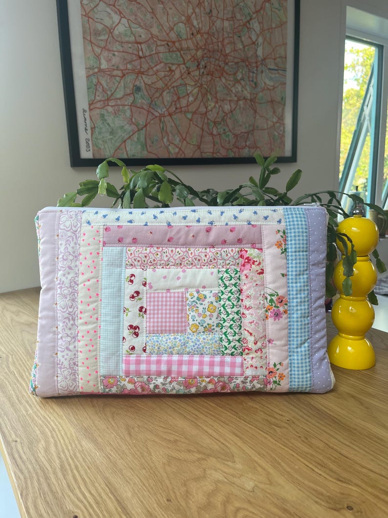 May include: A pink and blue patchwork quilt-style zippered pouch with a variety of floral and geometric patterns.