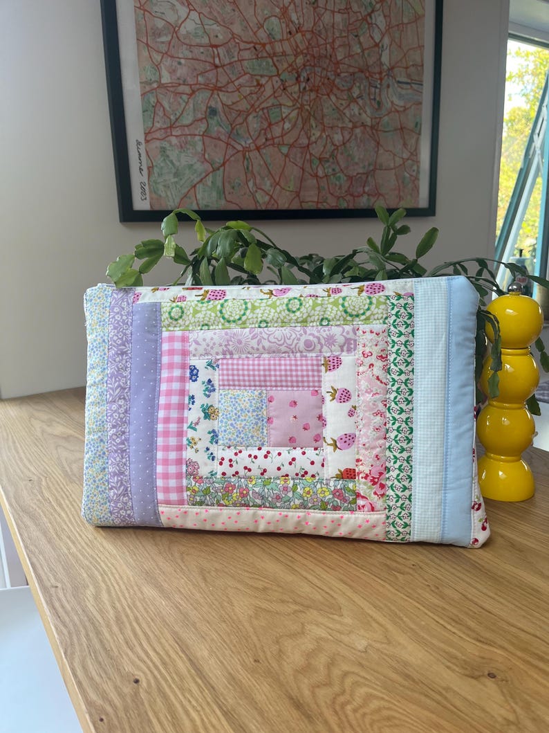 May include: A patchwork quilt-style zippered pouch with a variety of floral and geometric patterns in shades of pink, blue, and green.