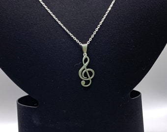 Puede incluir: Un collar de cadena de plata con un colgante de clave de sol.