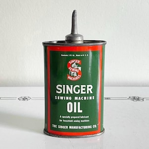 May include: A cylindrical metal can of Singer sewing machine oil with a green and red label. The text reads Singer Sewing Machine Oil, A specially prepared lubricant for household sewing machines, The Singer Manufacturing Co., and Contents 3 Fl. Oz.