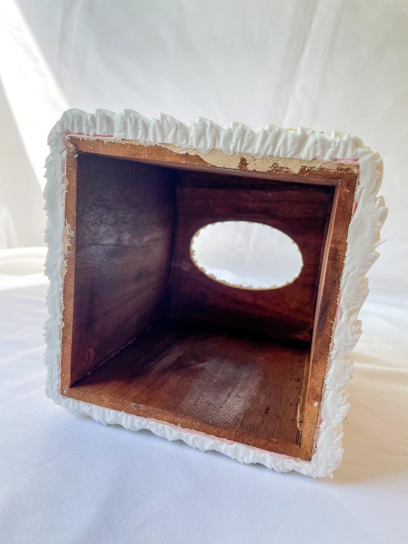 May include: White tissue box cover with a decorative, ruffled edge. The cover is made of a textured material and has a rectangular opening for tissues.