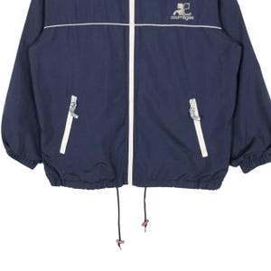 Puede incluir: Chaqueta azul marino con cremallera, ribetes blancos y el logo de Courreges. La chaqueta tiene un cord&oacute;n en la parte inferior y dos bolsillos delanteros. La chaqueta est&aacute; hecha de un material ligero.