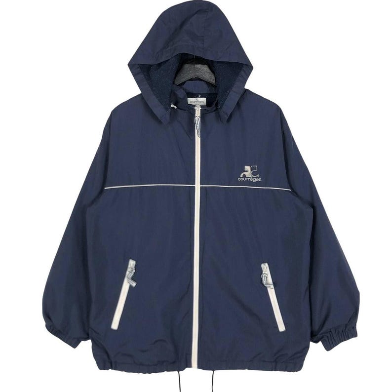 Puede incluir: Chaqueta con capucha azul marino con cremallera y ribetes blancos. La chaqueta presenta un logotipo en el pecho y dos bolsillos delanteros. La chaqueta tiene un cord&oacute;n en la parte inferior y una capucha.
