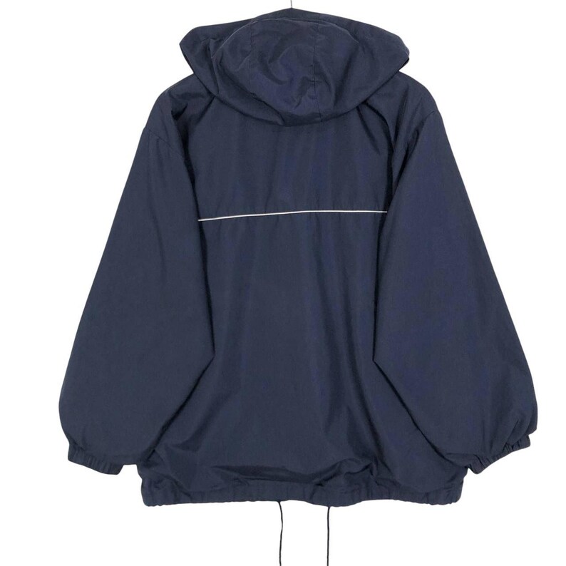 Puede incluir: Chaqueta con capucha azul marino con una raya blanca horizontal en la espalda. La chaqueta tiene un cord&oacute;n en la parte inferior y pu&ntilde;os el&aacute;sticos. La capucha est&aacute; adjunta y la chaqueta es de material ligero.