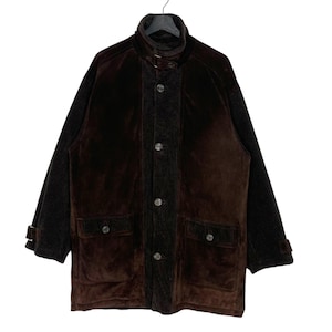 May include: A brown suede jacket with a corduroy center panel and dark knit sleeves. The jacket has a high collar, button closures, and two front pockets. The jacket is hanging on a black hanger.