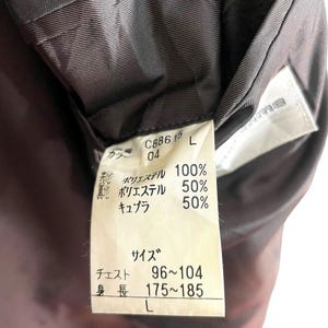 May include: Close-up of a garment tag with Japanese text. The tag is white with black text and includes fabric composition percentages. The tag also lists chest and height measurements, and the size is L.